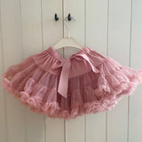 Roze Loli tutu rok met strik en uitwaaierende ruches aan een witte kledinghanger.