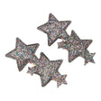 Twee Urfa haarclips met grote en kleine sterren, zwarte randen en veelkleurige glitters op een witte achtergrond.