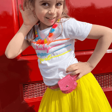 Meisje met de neonroze Urfa glitterriem met tasje, gedragen op een gele rok bij een wit shirt.