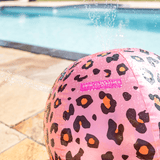 Detail van de roze watersproeier met zwarte en oranje panterprint en waterstralen naast het zwembad.